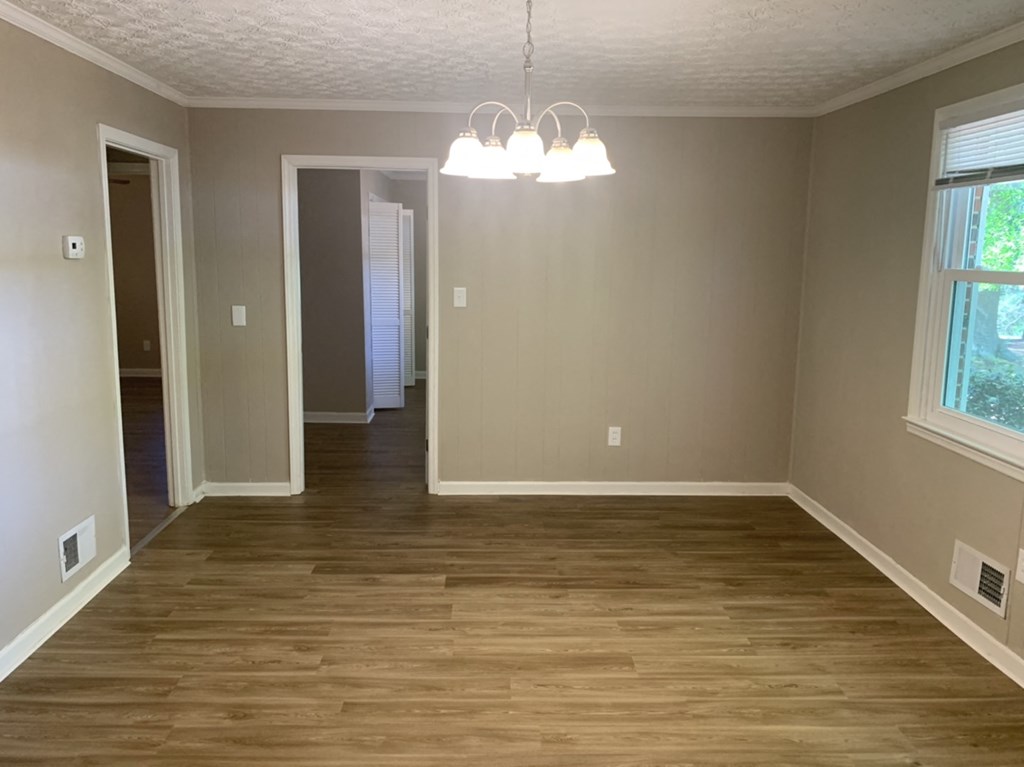 an empty living room with wood floors and a chandelier