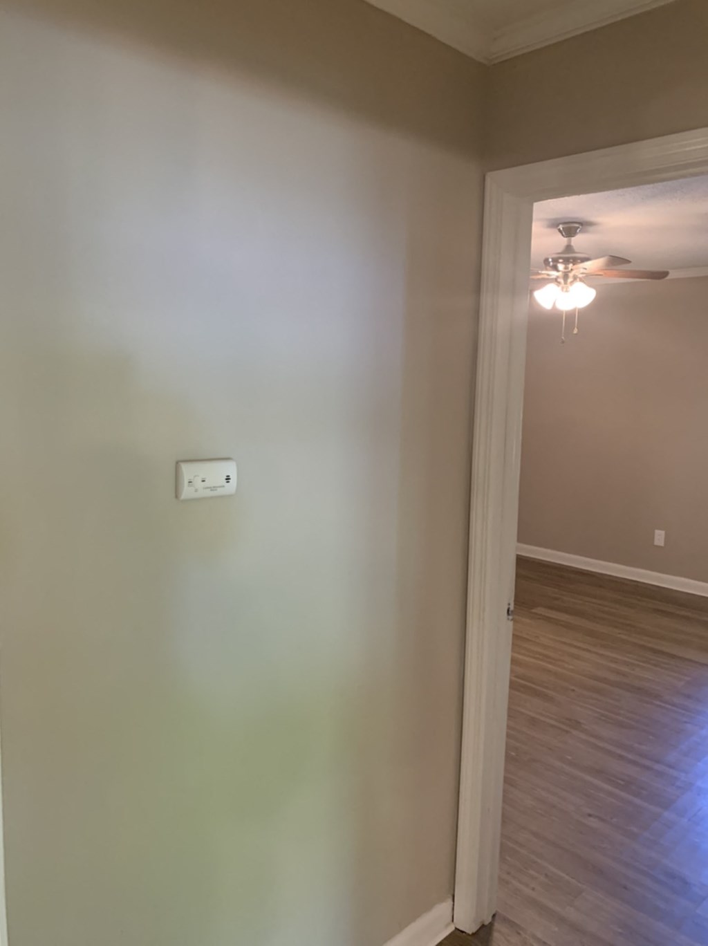 an empty room with a white wall and a ceiling fan