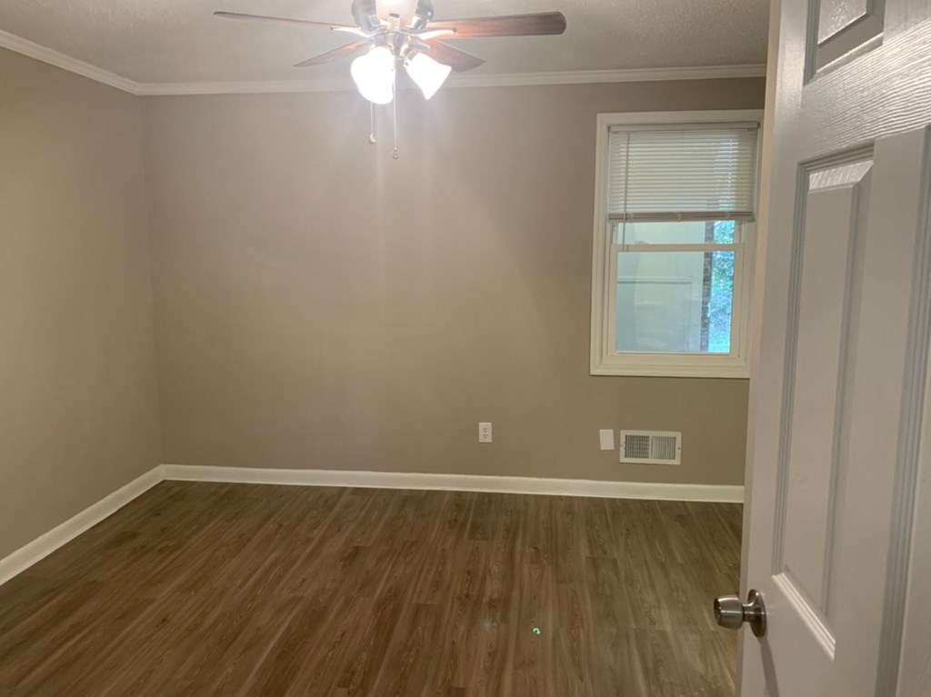 a bedroom with a wood floor and a ceiling fan