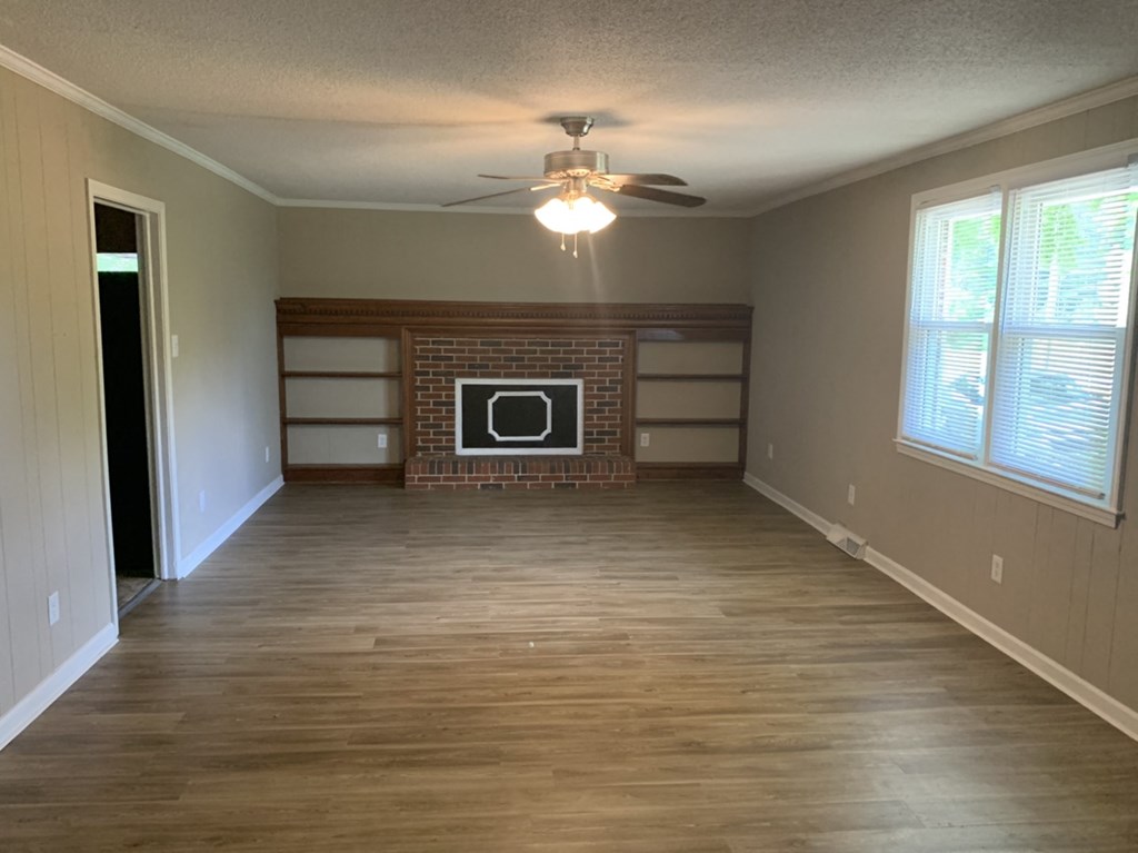 an empty living room with a ceiling fan and a fireplace