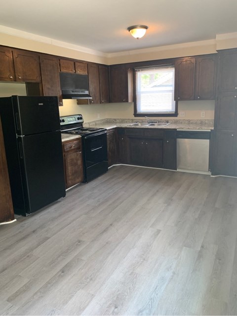 A kitchen with black appliances and wooden cabinets.