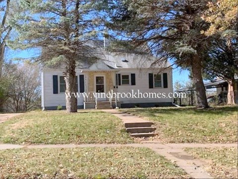 a small white house with trees and a sidewalk