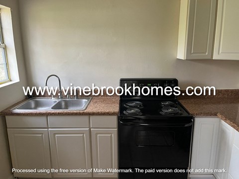 a kitchen with white cabinets and a black stove and a sink