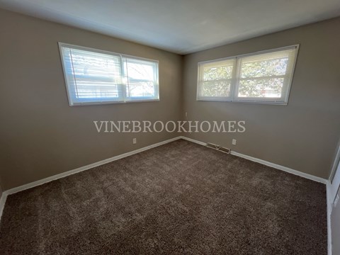 a living room with a carpet and two windows