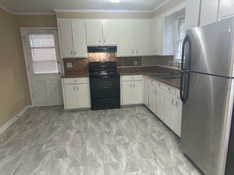 a kitchen with white cabinets and a black stove and refrigerator