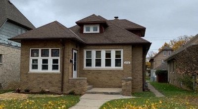 a small brick house with a sidewalk in front of it