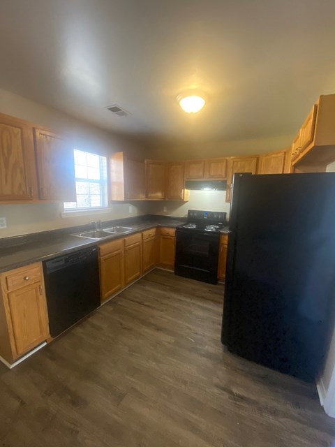 A kitchen with wooden cabinets and black appliances.