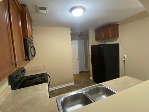 A kitchen with a black fridge and stove top oven.
