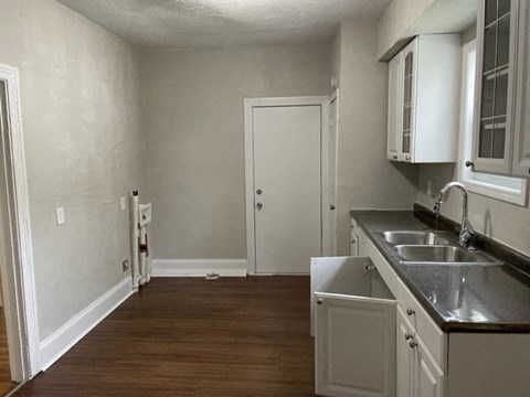A kitchen with white cabinets and a white door.