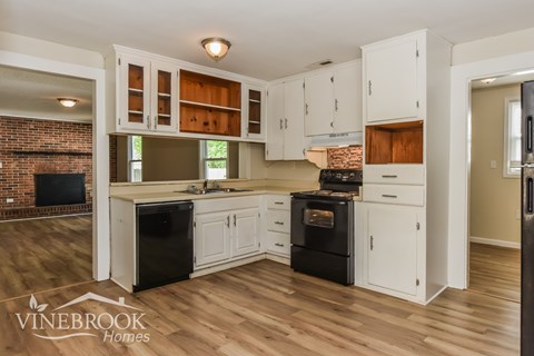 A kitchen with white cabinets and a brick wall.