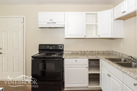 A black stove in a kitchen with white cabinets.
