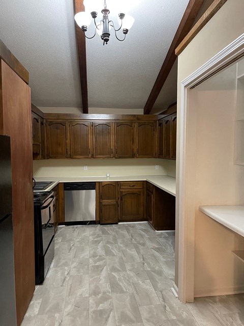 A kitchen with wooden cabinets and a tile floor.