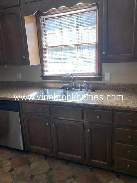 A kitchen with brown cabinets and a stone countertop.