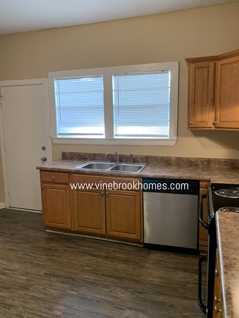 A kitchen with wooden cabinets and a stainless steel dishwasher.