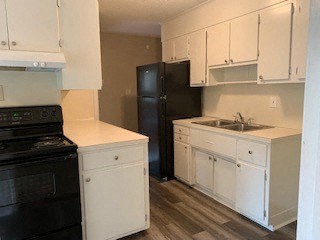 A kitchen with black appliances and white cabinets.