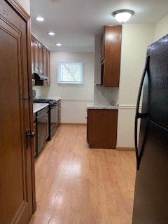 a kitchen with a wooden floor and a black refrigerator