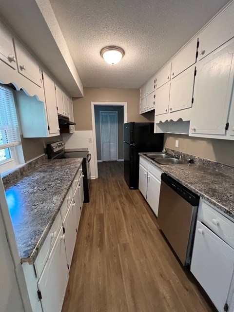 A kitchen with white cabinets and a black refrigerator.