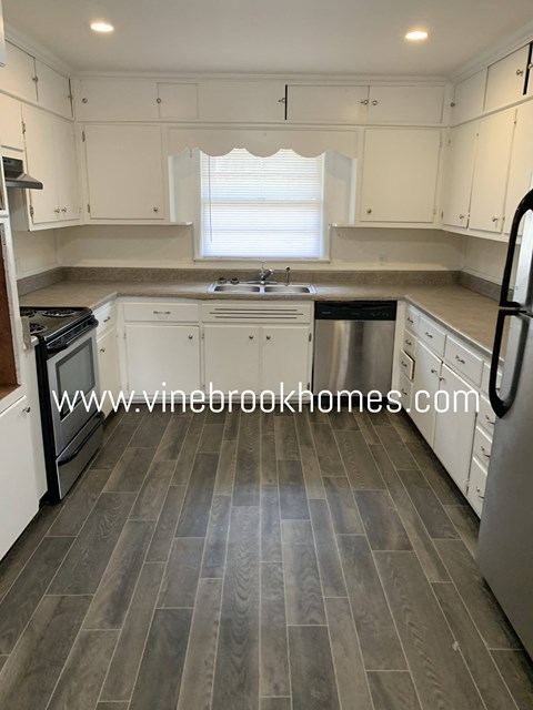 A kitchen with white cabinets and a grey floor.