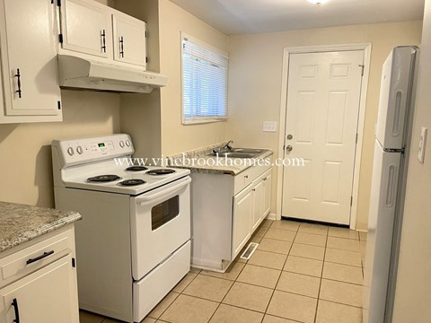 a kitchen with white appliances and white cabinets and a white door