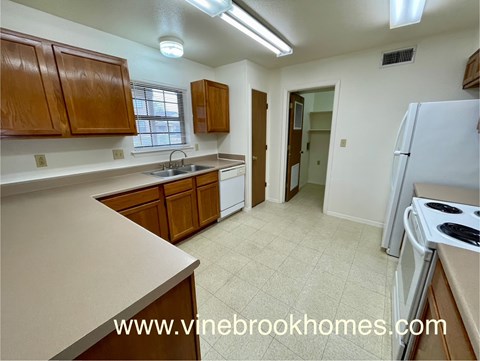 A kitchen with a white refrigerator and brown cabinets.