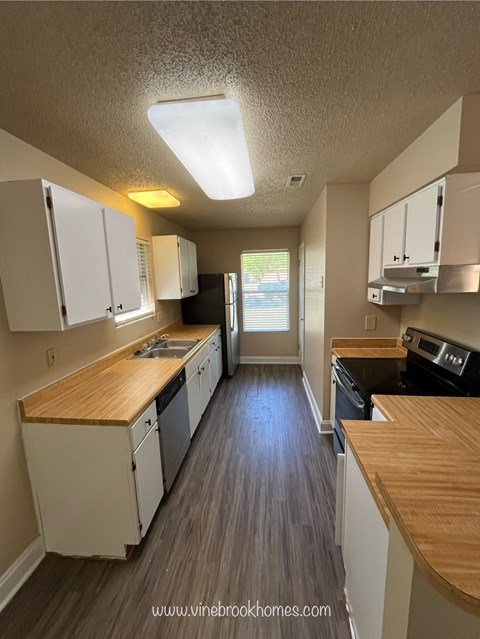 A kitchen with white cabinets and a wooden countertop.