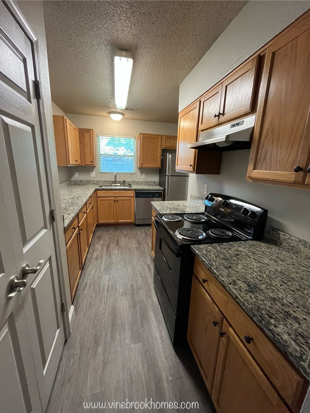 A kitchen with wooden cabinets and a granite countertop.