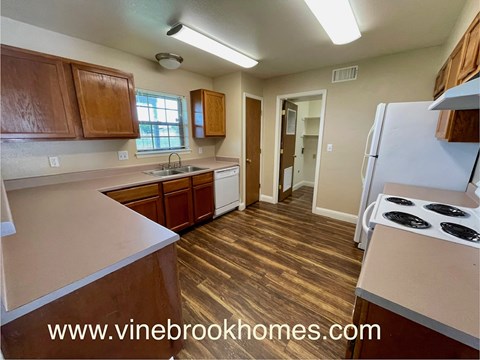 A kitchen with wooden cabinets and a white stove top oven.