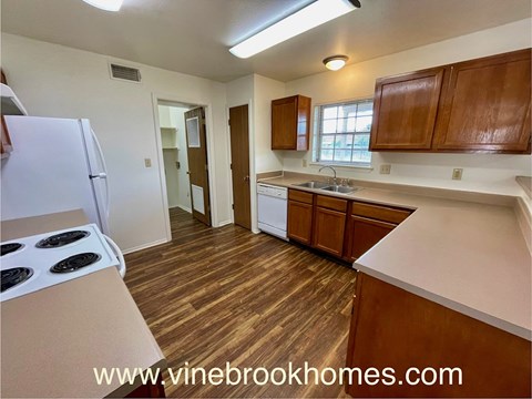 A kitchen with a white fridge and wooden floors.
