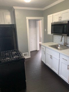 A black refrigerator sits next to a black microwave in a kitchen.