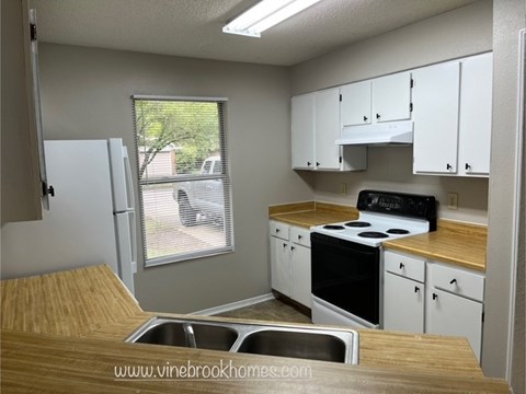 A kitchen with white cabinets and a black stove top oven.