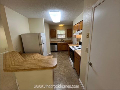 A kitchen with a refrigerator, stove, and sink.