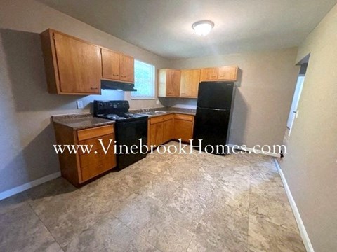 A kitchen with wooden cabinets and a black refrigerator.