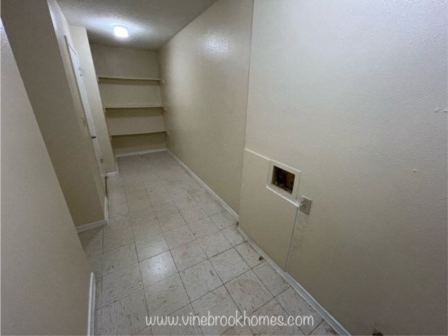 a hallway with shelves on the wall and a tiled floor