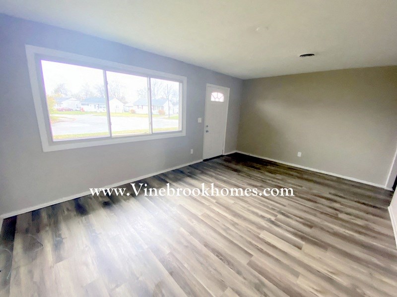 an open living room with hardwood floors and a large window