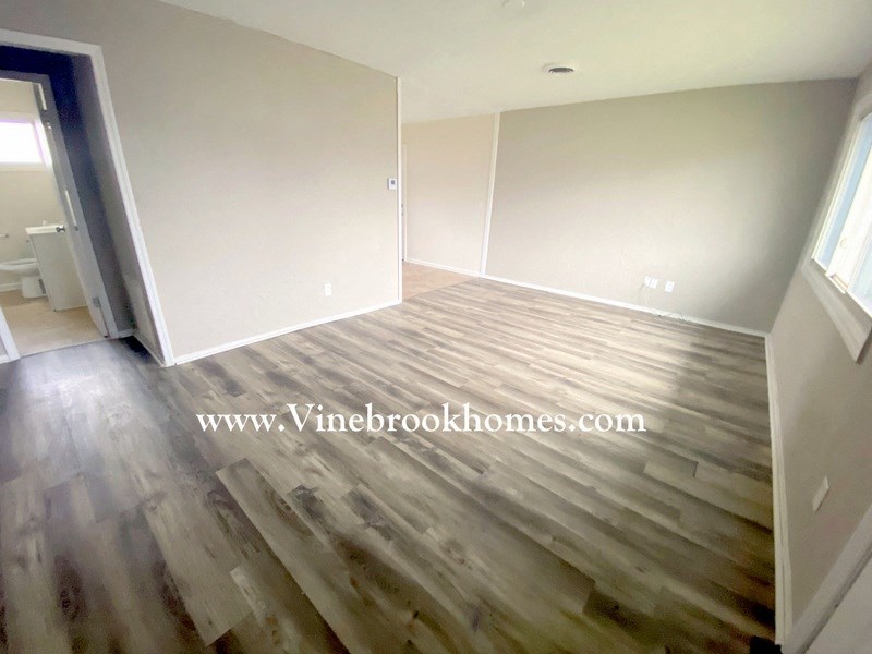the living room has hardwood flooring and a door to the bathroom