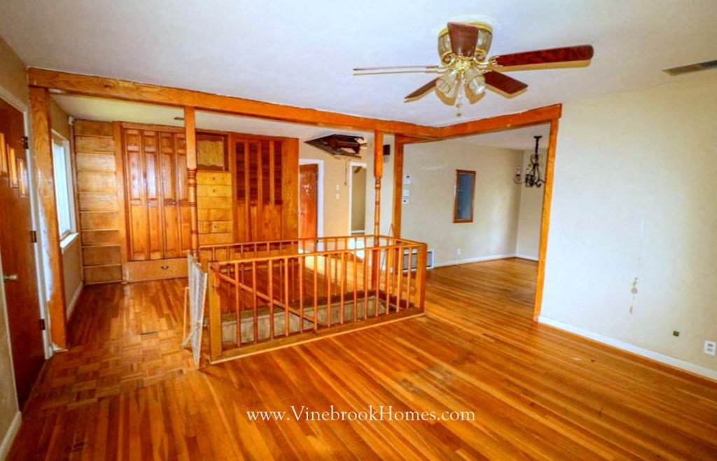 an empty living room with wood floors and a ceiling fan