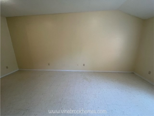 an empty room with white flooring and tan walls