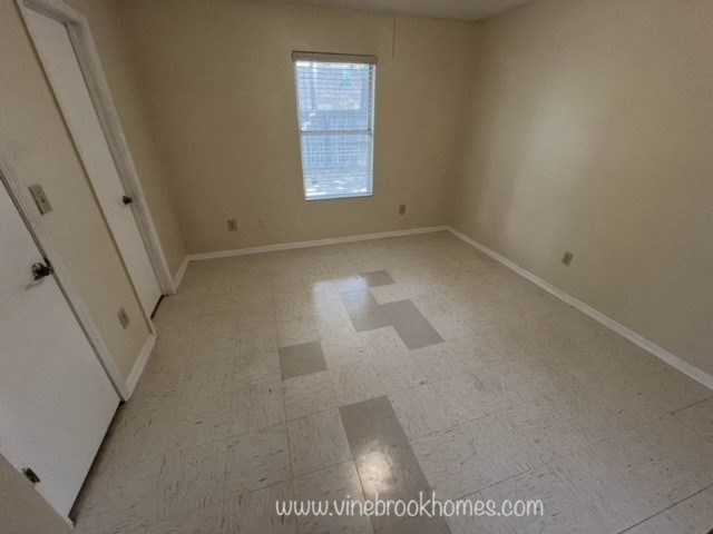 an empty room with white tile and a window
