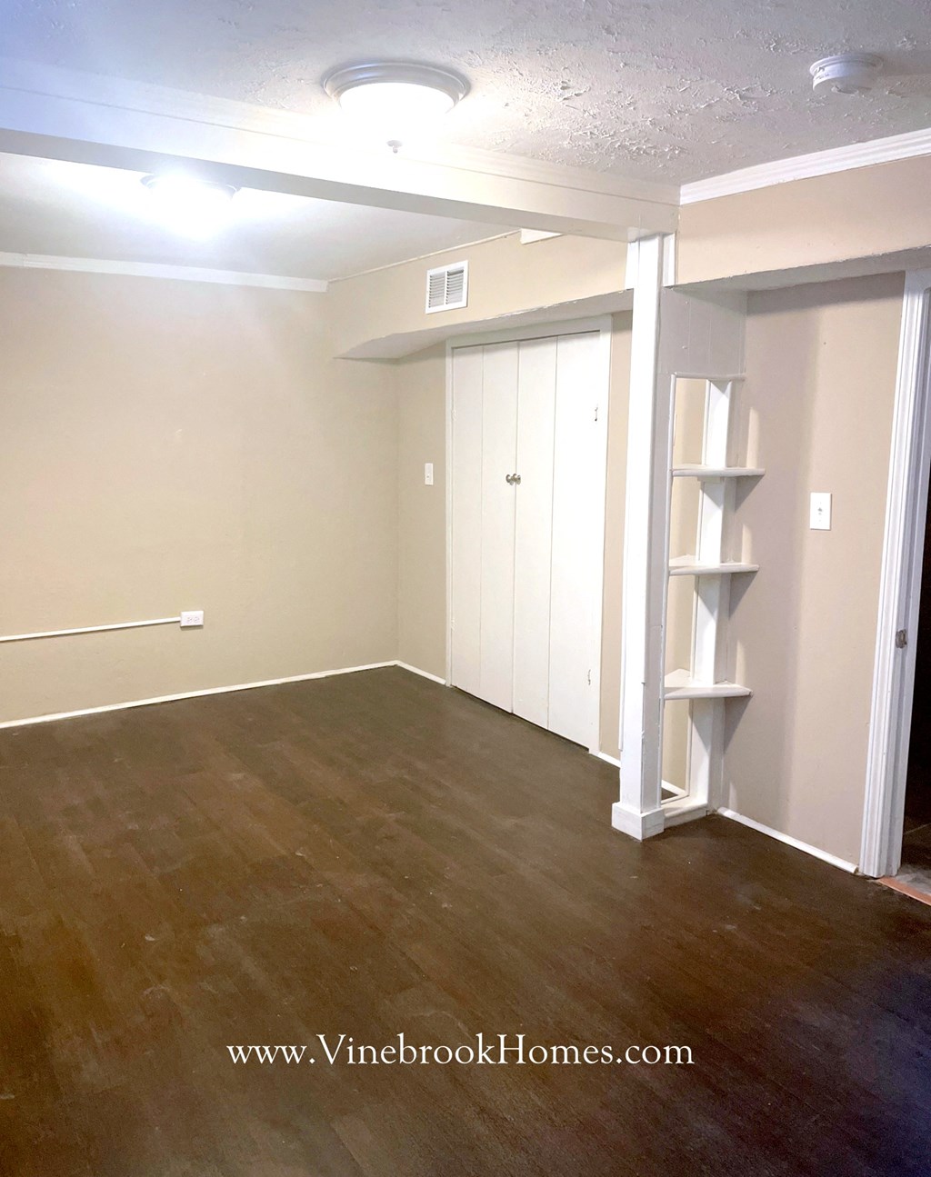a room with a wood floor and white walls and a closet and a white shelf