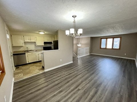 an empty living room and kitchen with wood floors