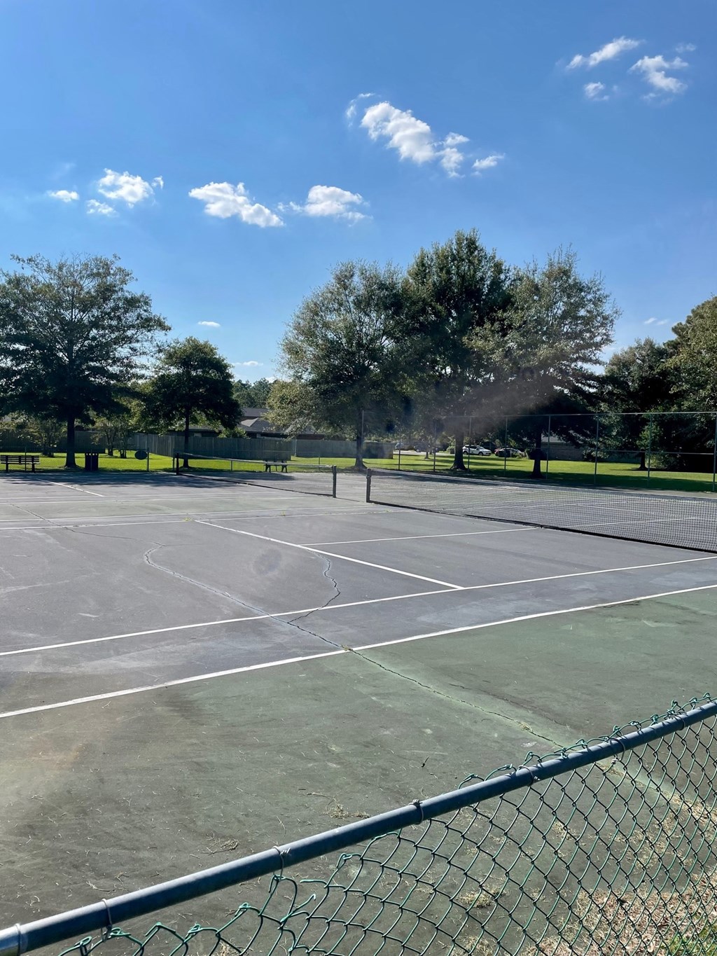 a tennis court with trees and a fence
