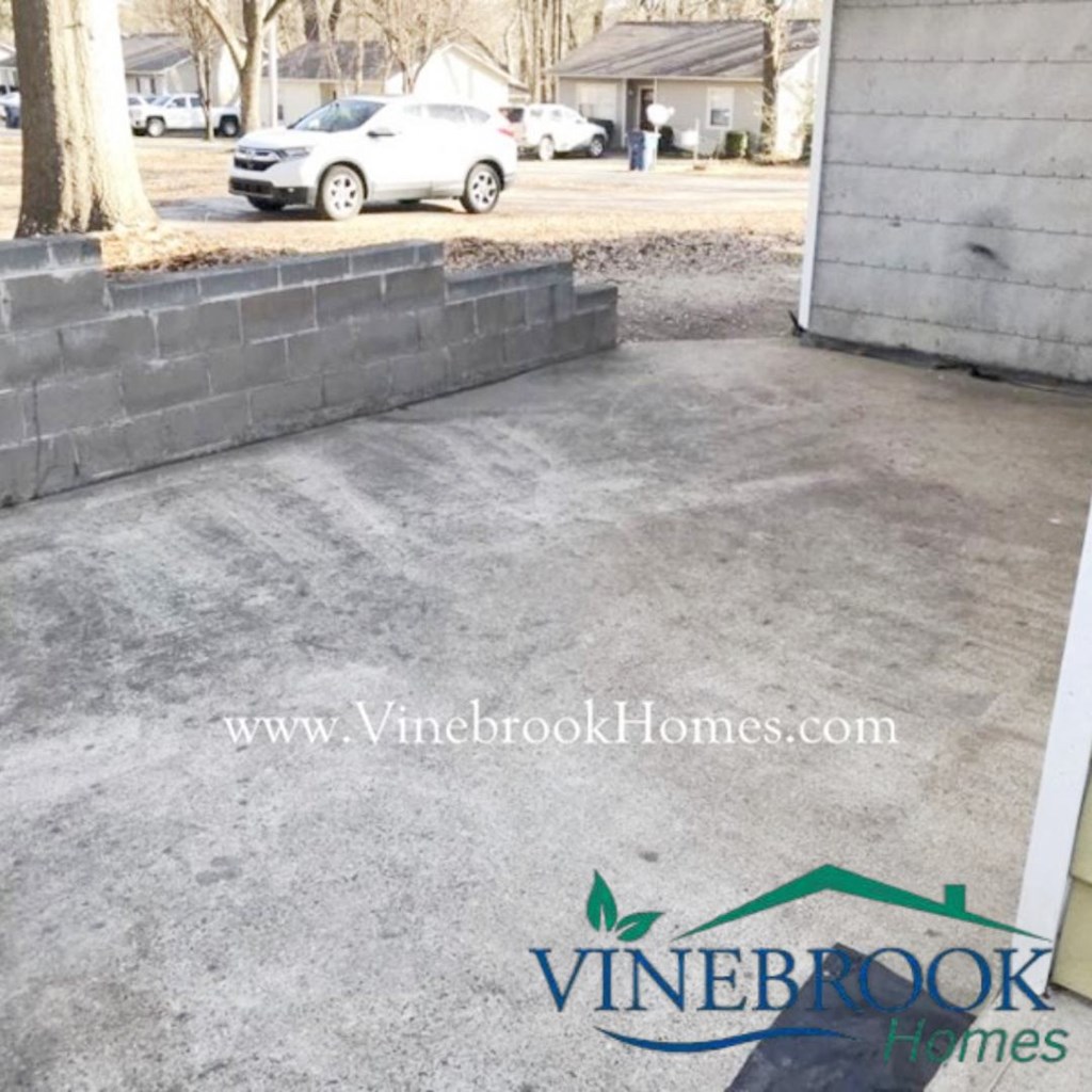 a concrete driveway with a brick retaining wall and a
