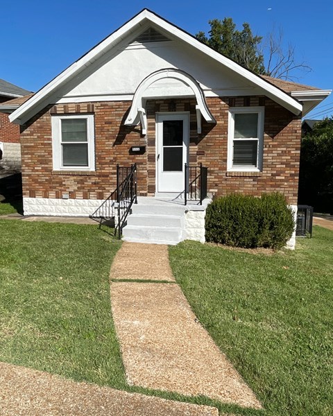 a small brick house with a sidewalk in front of it