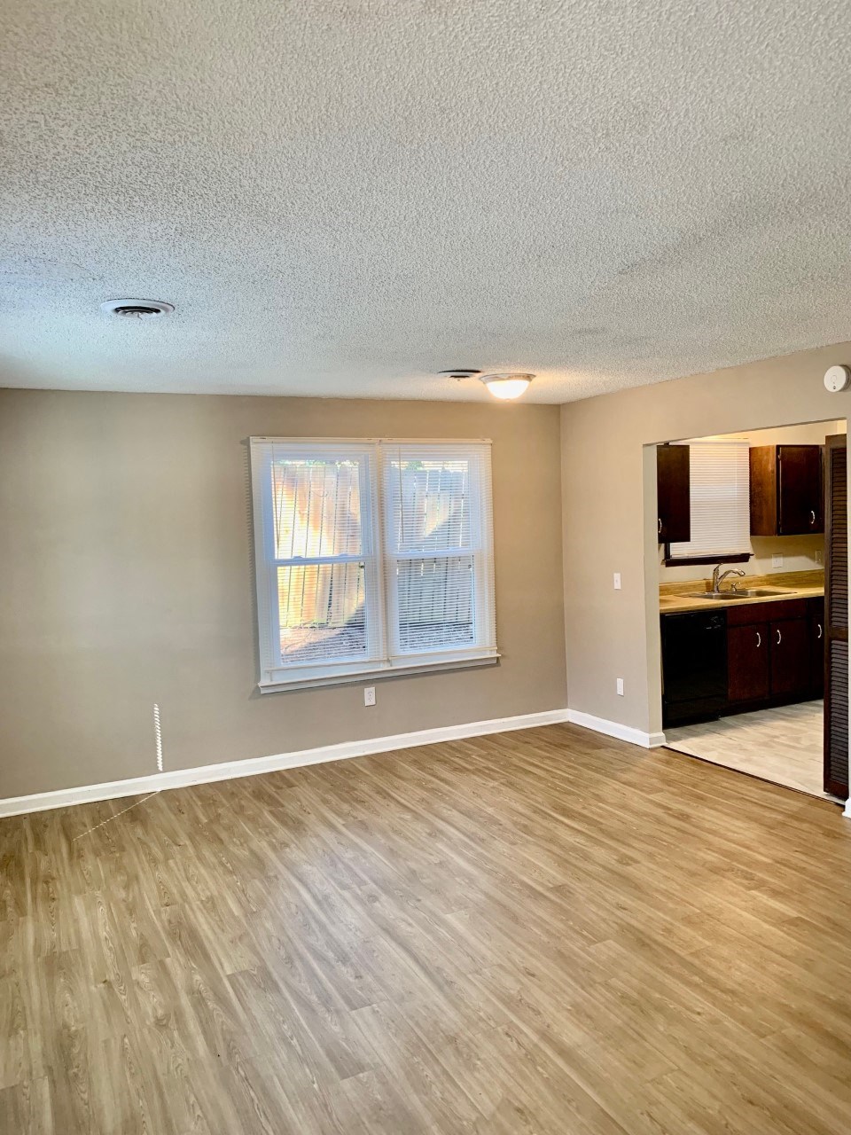 an empty living room with wood floors and a window