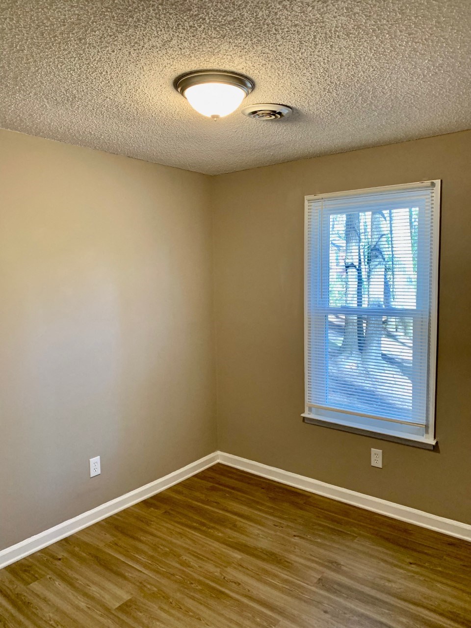 an empty room with a window and wooden floors