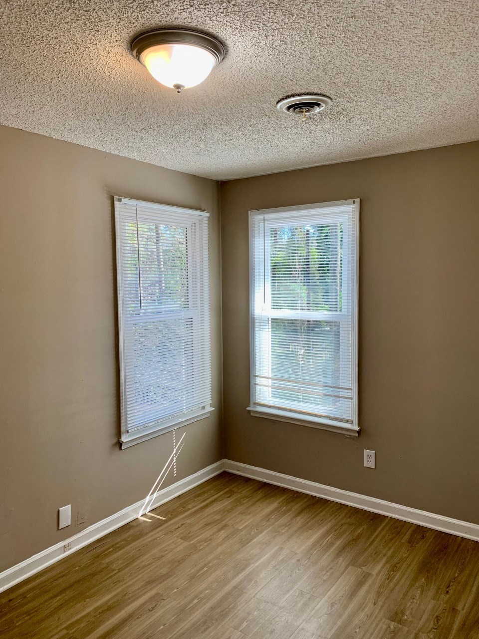 an empty room with a hard wood floor and two windows