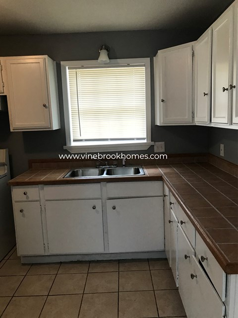 A kitchen with white cabinets and a brown countertop.