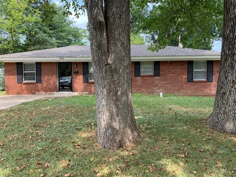 A red brick house with a black car parked in front.