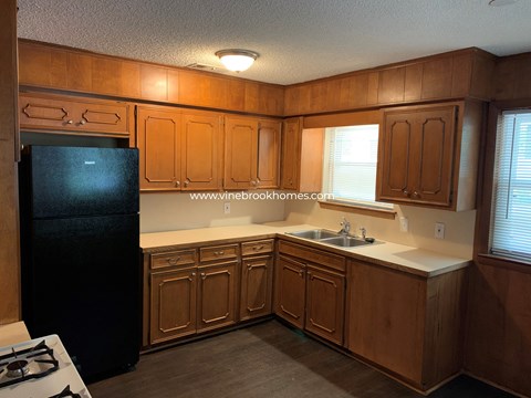 A kitchen with wooden cabinets and a black refrigerator.