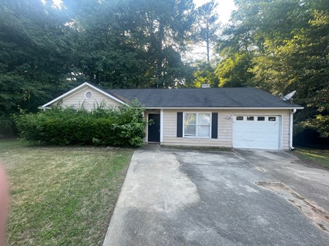 a small white house with a driveway and a garage door